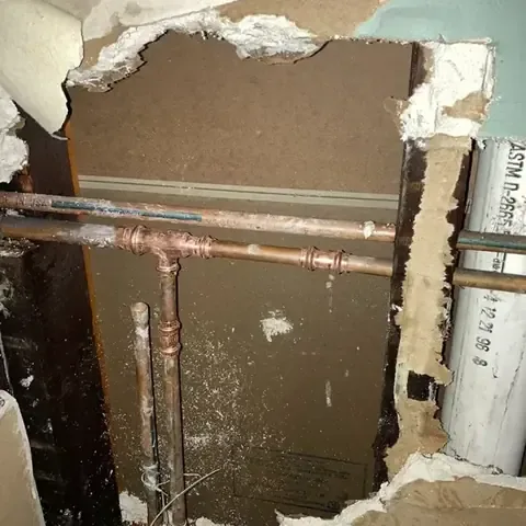 Section of wall cut open to reach a leaking copper supply line