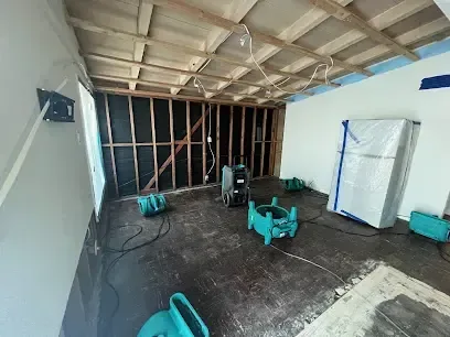 Air movers drying exposed framing in a room with opened walls and ceiling